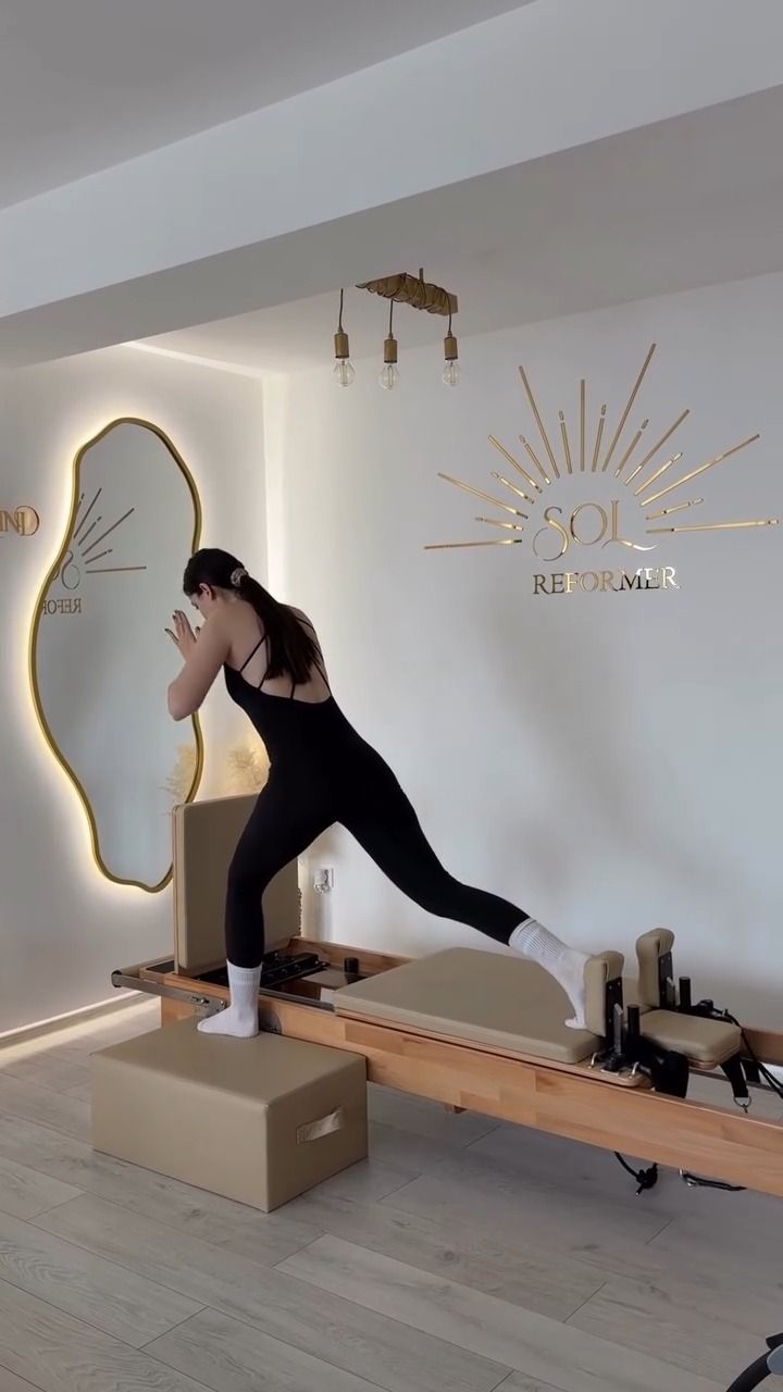 Clientă într-un fandat pe reformer, cu logo-ul SOL pe peretele din spate