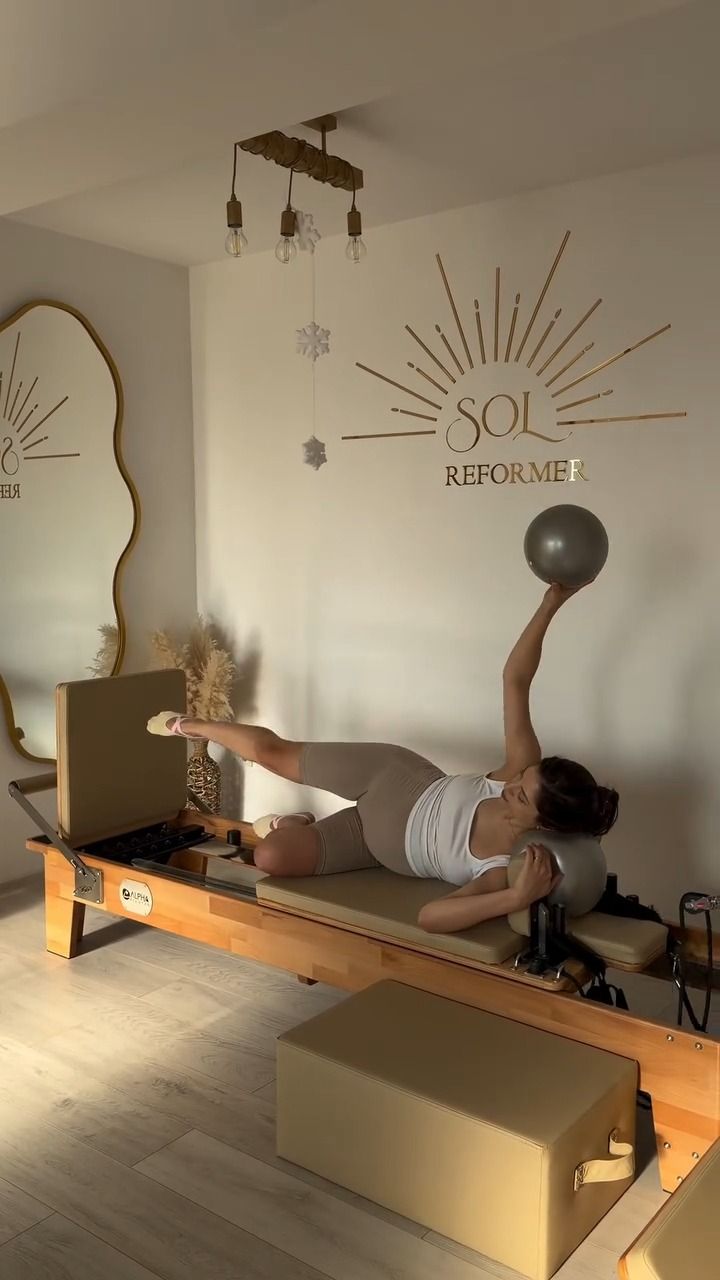 Exercițiu lateral cu minge de pilates pe reformer, sub logo-ul SOL
